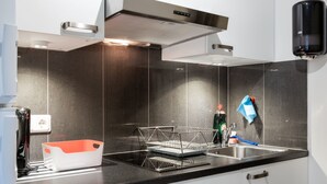 A modern kitchen with a stainless steel range hood, a dish rack, and a sink.