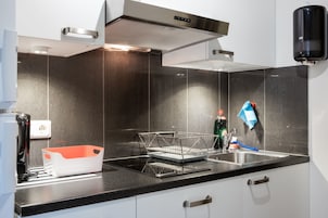A modern kitchen with a stainless steel range hood, a dish rack, and a sink.