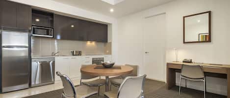 Una cocina moderna con electrodomésticos de acero inoxidable, un comedor con una mesa redonda y sillas, y un escritorio con una silla.