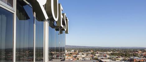 Un balcón con vistas despejadas de la ciudad, una mesa con sillas y un letrero que dice "QUEST".