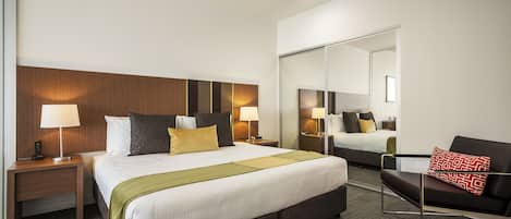 Une chambre d’hôtel avec un grand lit, des tables de chevet avec des lampes, un canapé et un miroir.