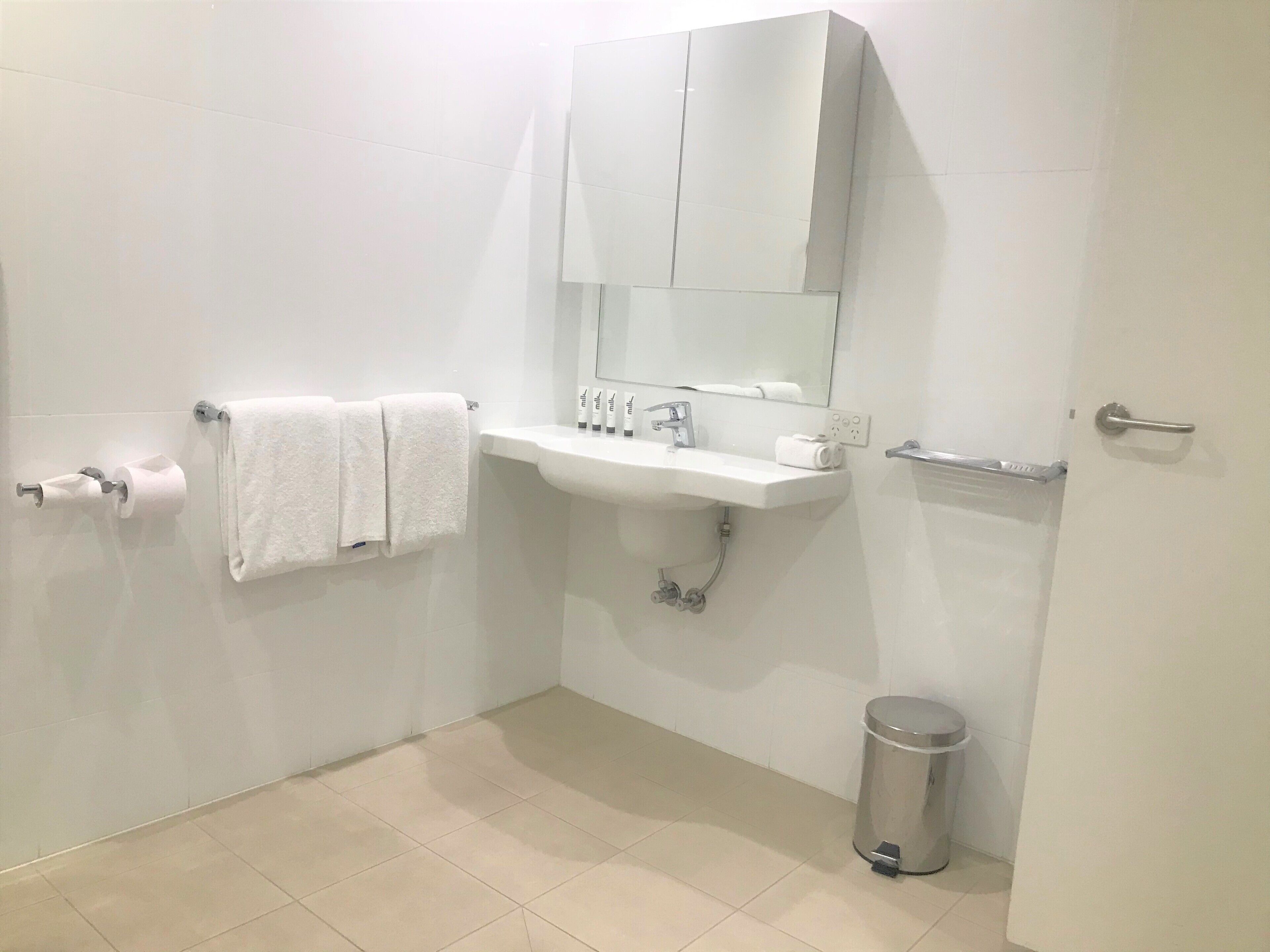 Un baño moderno con lavamanos blanco, espejo y toallero.
