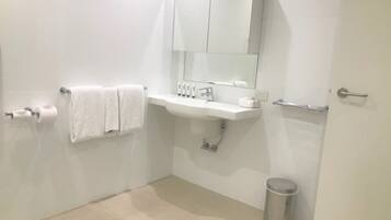 Un baño moderno con lavamanos blanco, espejo y toallero.