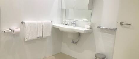 Un baño moderno con lavamanos blanco, espejo y toallero.