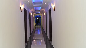 Un pasillo largo y estrecho con piso reflectante, iluminación empotrada y apliques de pared.