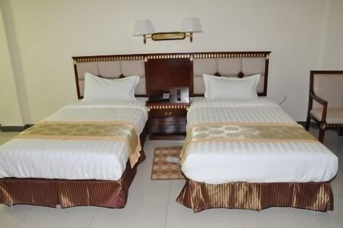 A double bed with a wooden headboard and two bedside tables, each with a lamp.