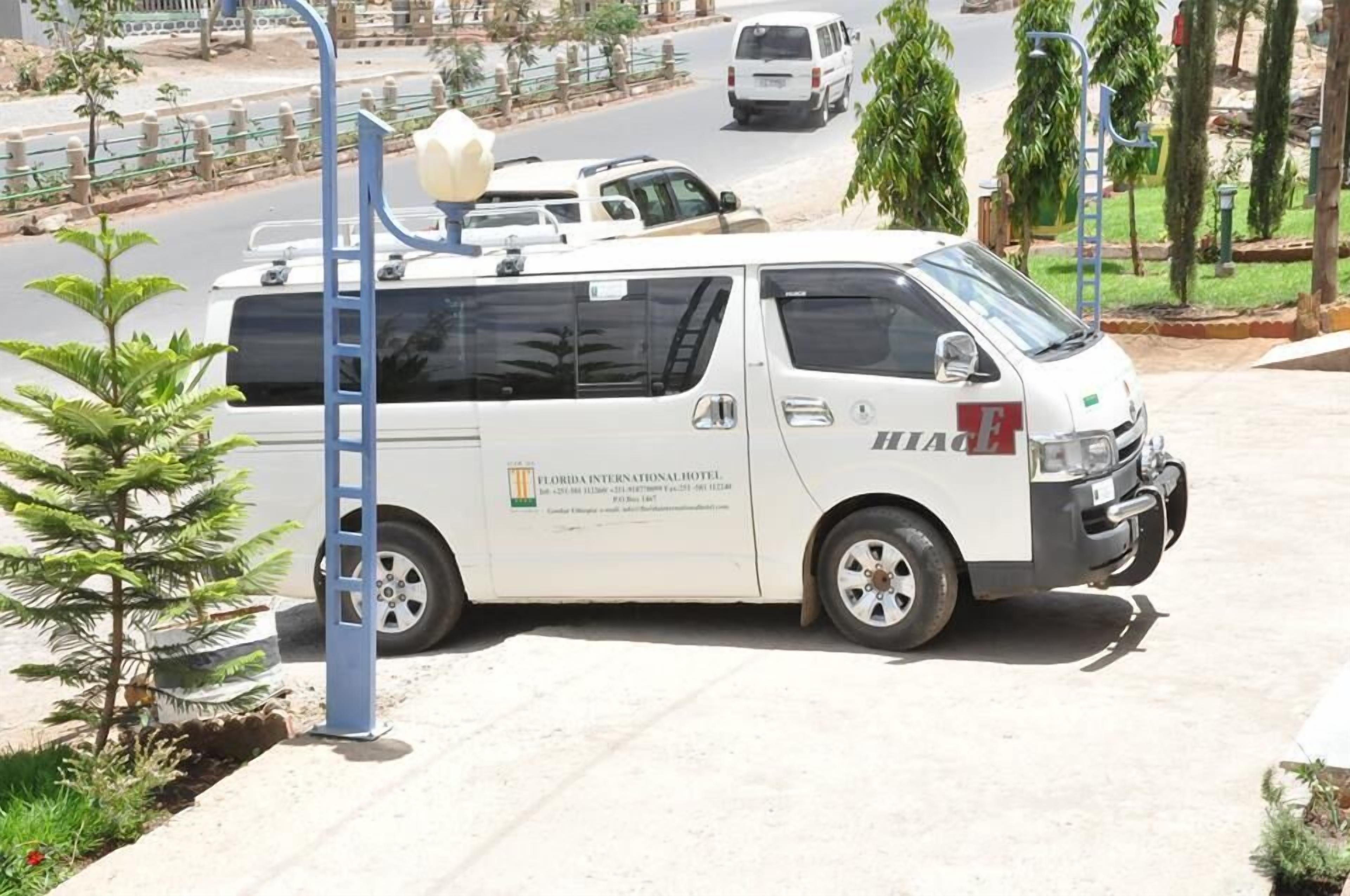 A white van parked on a street with a ladder attached to it.