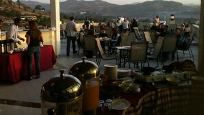 Un área de comedor al aire libre con mesas y sillas, un bufé y vistas del paisaje circundante.