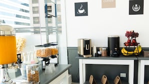 A coffee station with a coffee machine, a coffee pot, and a fruit display.