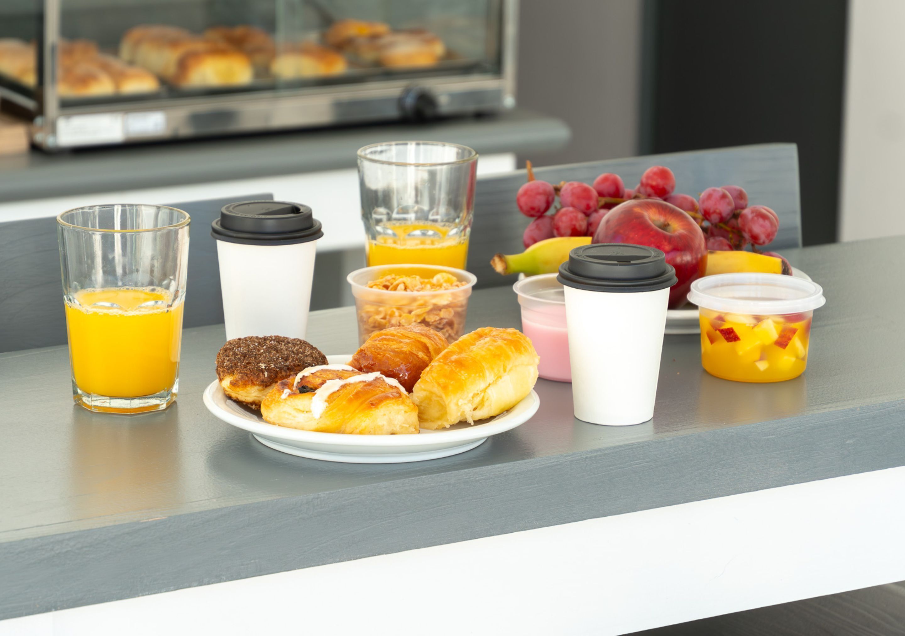 Mesa posta para o café da manhã, com pães, frutas e bebidas.