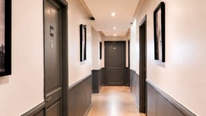 A hotel hallway with doors numbered 205 and 210, framed artwork on the walls, and a light-colored floor.
