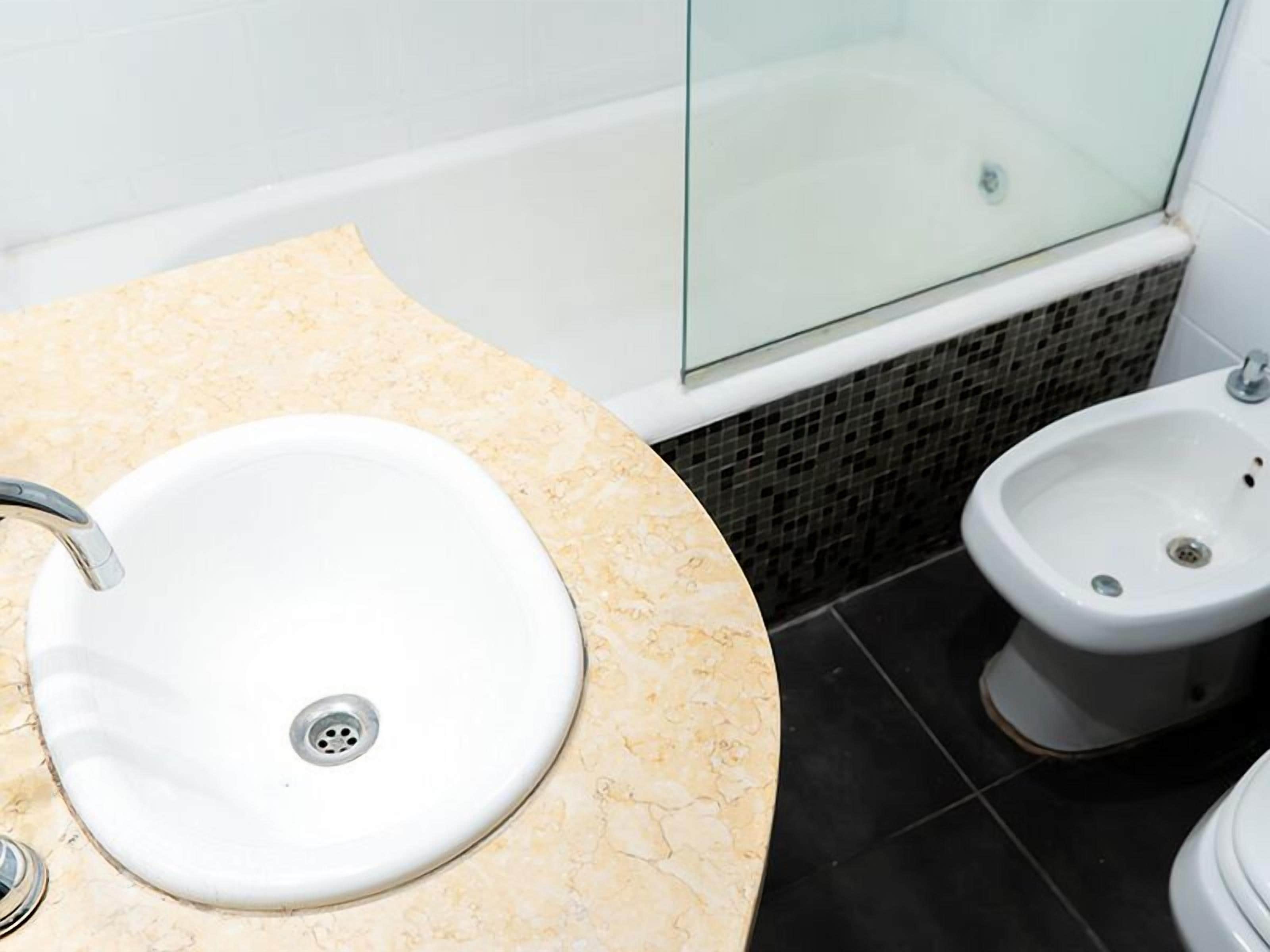 A bathroom with a sink, bidet, and bathtub.