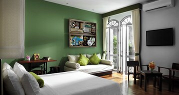 Habitación de hotel con dos camas, un sofá, una mesa de comedor y un televisor.
