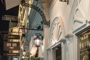 Un edificio histórico con detalles arquitectónicos ornamentales, incluyendo un letrero de hierro forjado que dice 'On On Hotel' y una farola.