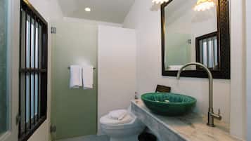 Een badkamer met toilet, een groene wastafel, een spiegel en een douche.