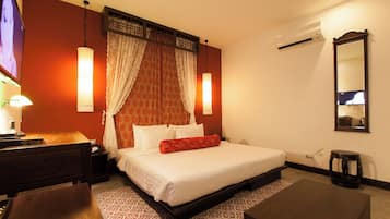 A hotel room with a bed, bedside table, lamp, and a large mirror.