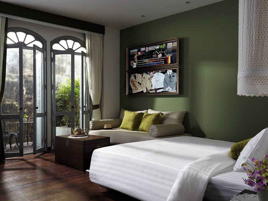 Een slaapkamer met een groot bed, een sofa, een kleine tafel en een tv aan de muur.