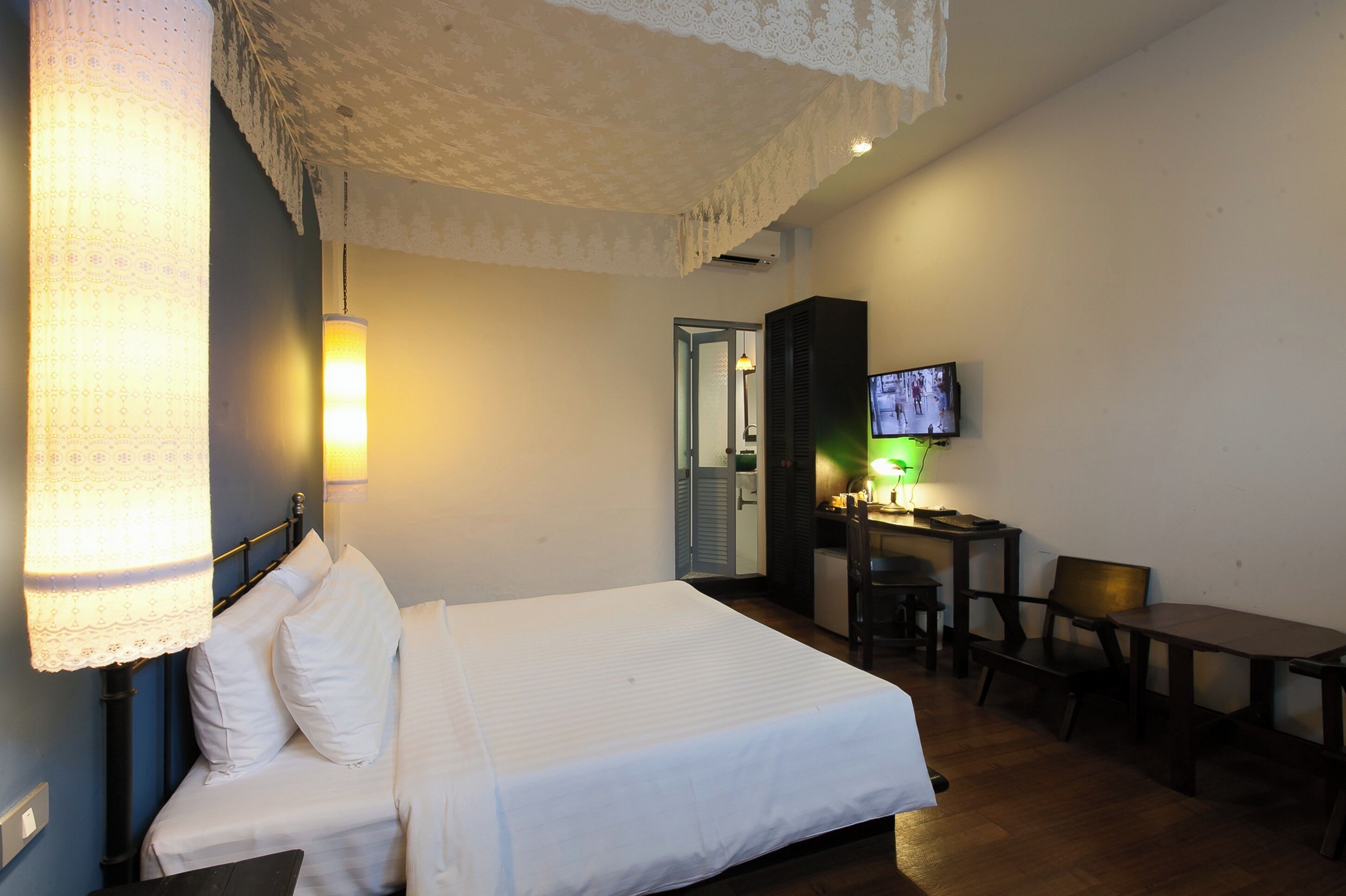 Una habitación de hotel con cama, escritorio, silla y televisor.