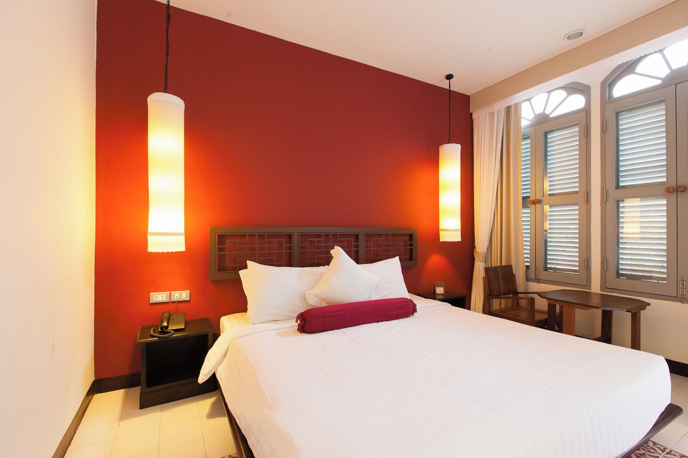 Une chambre d’hôtel avec un grand lit, une table de chevet avec un téléphone, un bureau et une chaise.