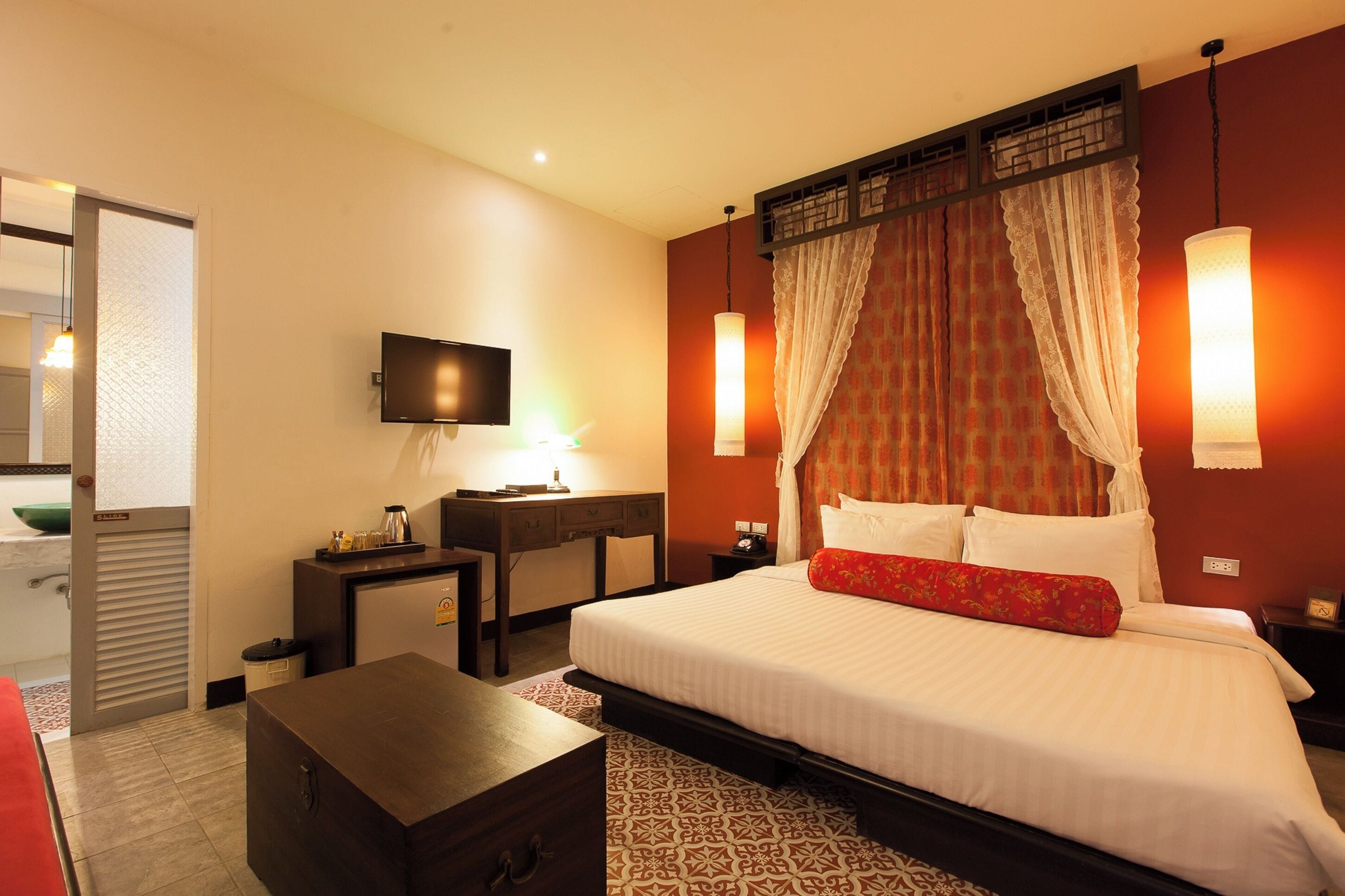 A hotel room with a bed, bedside table, desk, and a television.