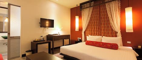 A hotel room with a bed, bedside table, desk, and a television.