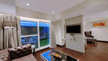 Un salon moderne avec une table basse en verre, un canapé en cuir et un grand téléviseur à écran plat fixé au mur.