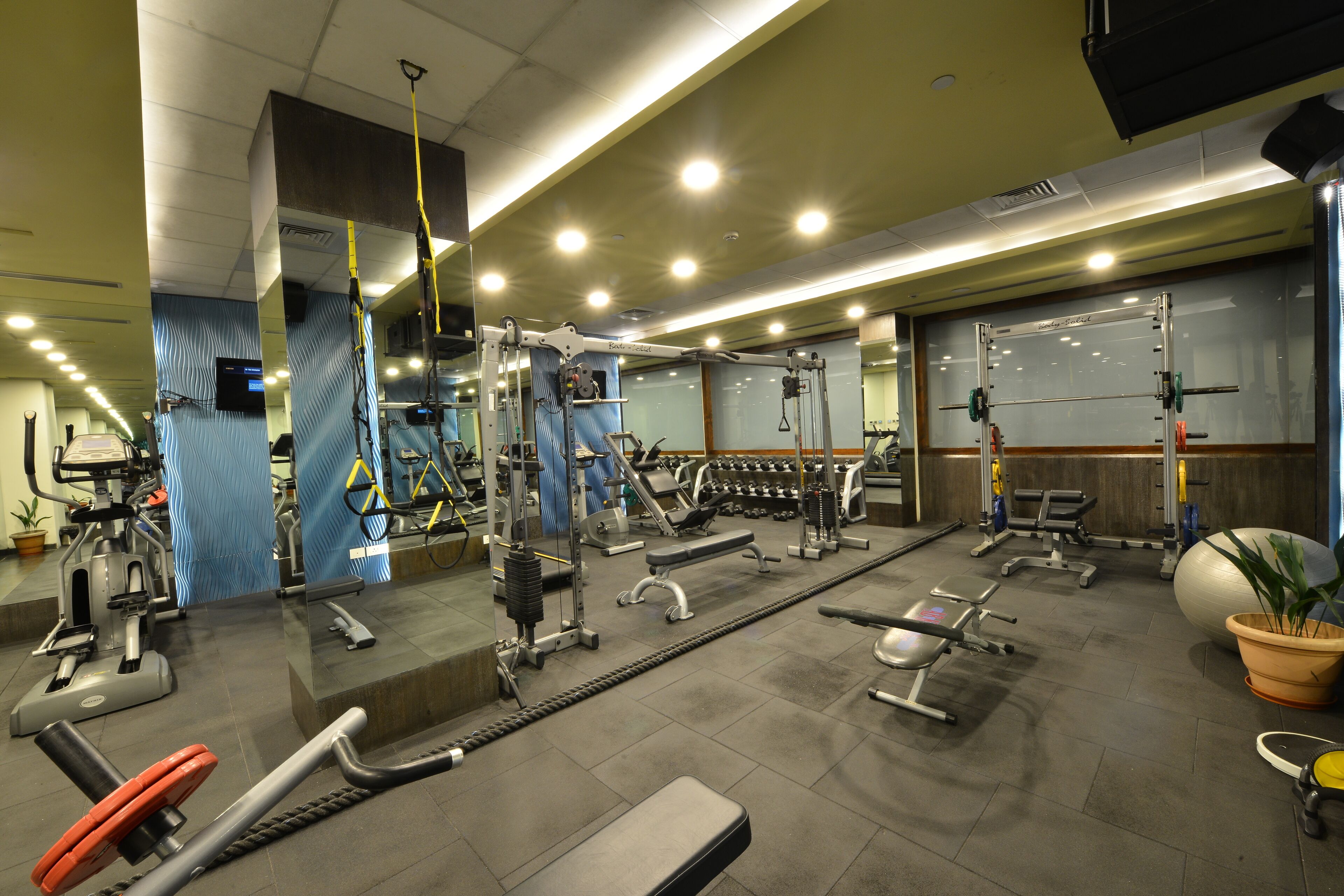 A gym with various exercise equipment, including treadmills, weight machines, and free weights.