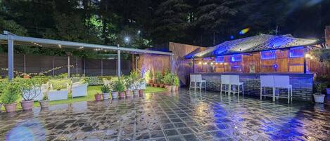 An outdoor patio area with stone flooring, potted plants, and seating.