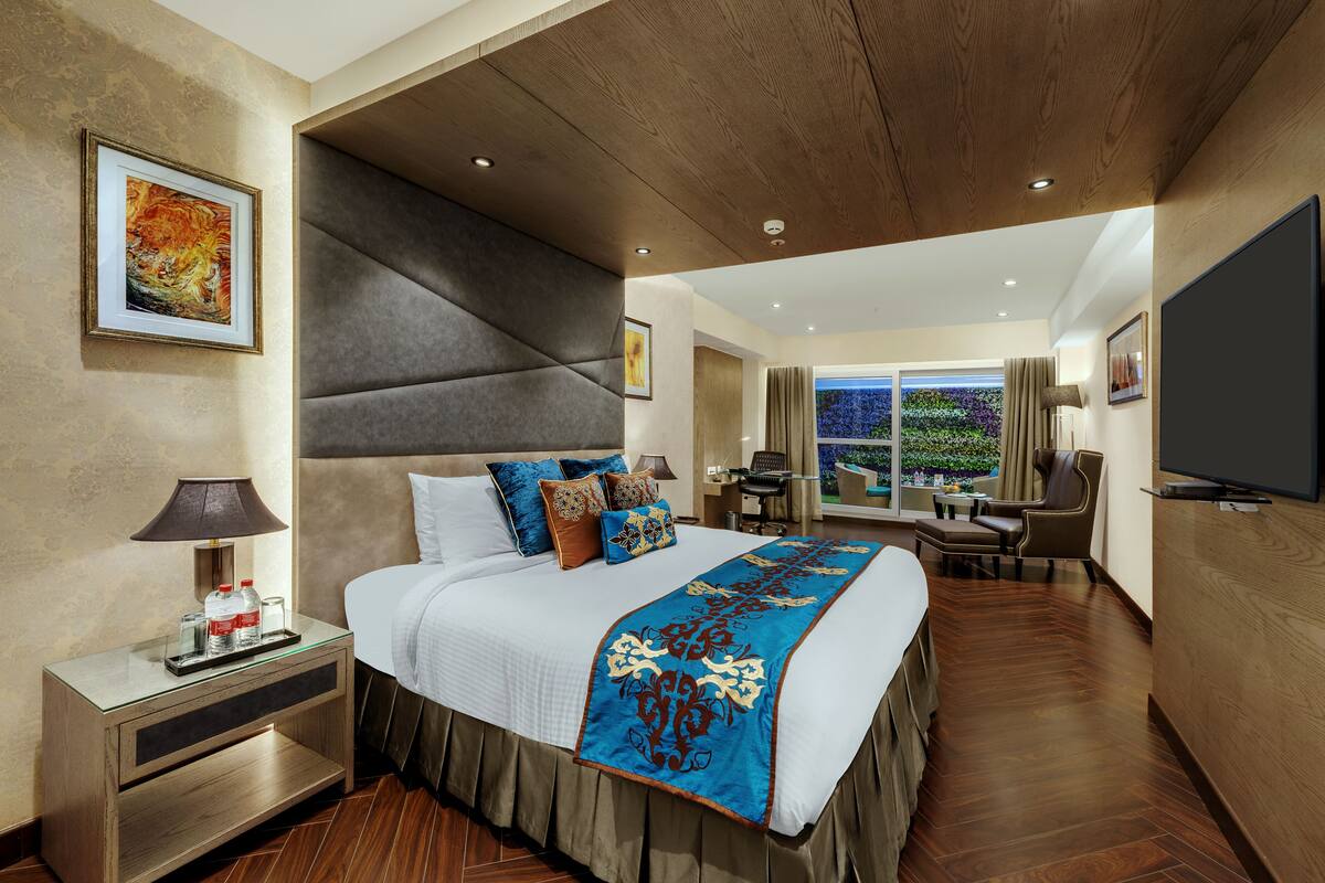 Una habitación de hotel moderna con una cama grande, un escritorio y un televisor.