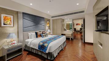 Habitación de hotel moderna con una cama grande, mesitas de noche, un televisor y vistas al comedor.