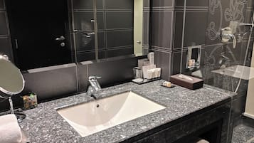 A modern bathroom with a granite countertop, a white sink, a mirror, and a towel rack.