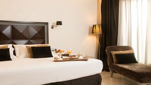 Une chambre d’hôtel avec un grand lit, une chaise, une petite table avec des articles pour le petit-déjeuner et une lampe.