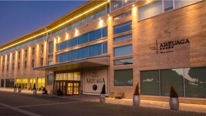 Un hôtel à l’architecture moderne, doté de grandes fenêtres et d’une enseigne indiquant « HÔTEL ARZUAGA BODEGAS ».