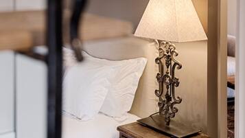 A neatly made bed with white linens, a wooden nightstand with a lamp, and a mirror on the wall.