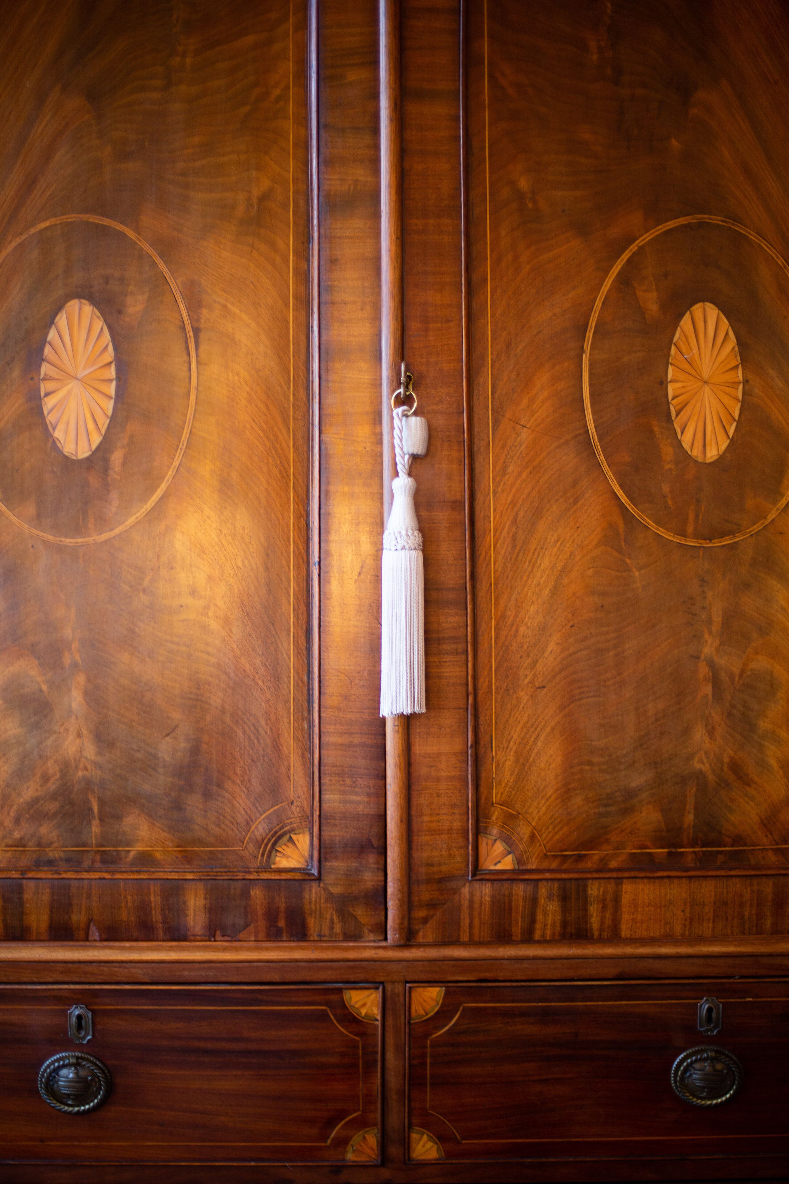 Un mueble de madera con dos aberturas circulares y un cascabel colgante.