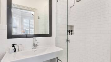 A bathroom with a white sink, a mirror, and a shower.