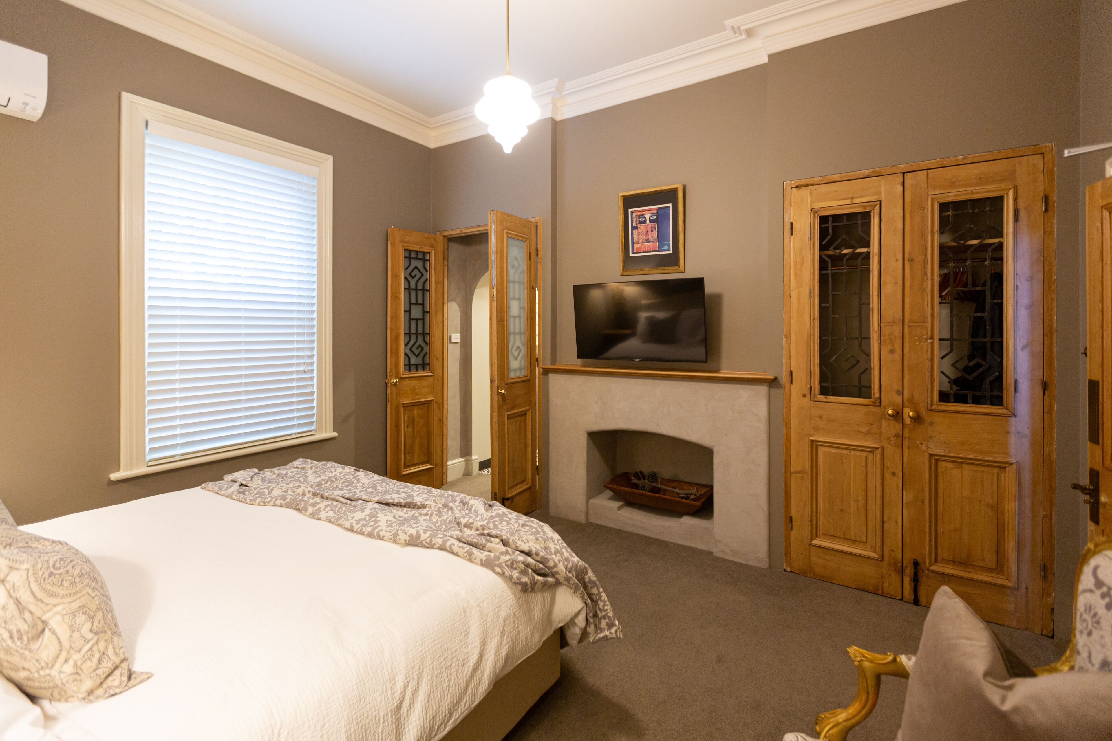 Un dormitorio con cama, televisión, chimenea y puertas de madera.