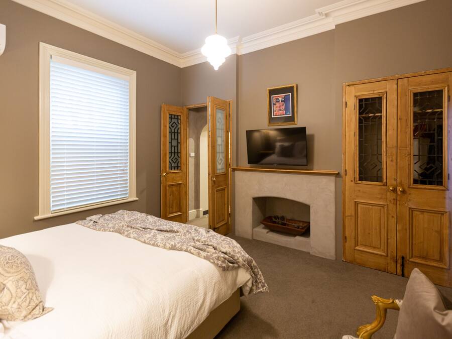 Un dormitorio con cama, televisión, chimenea y puertas de madera.