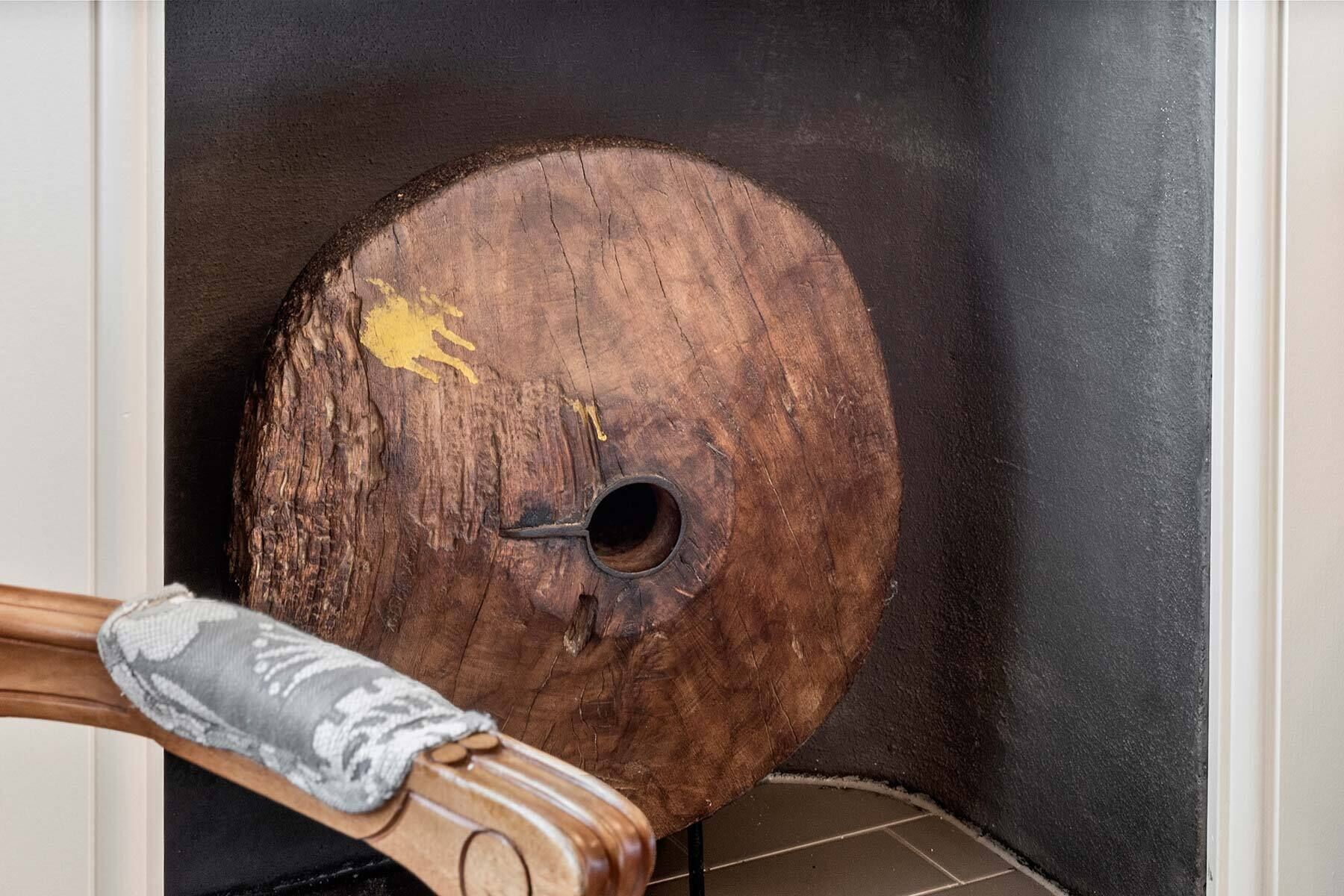 A wooden object with a circular hole and a yellow mark, placed against a dark background.