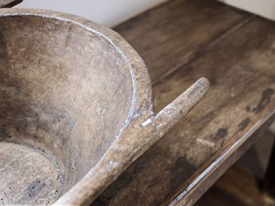 A rustic wooden table with a worn surface and a handle.