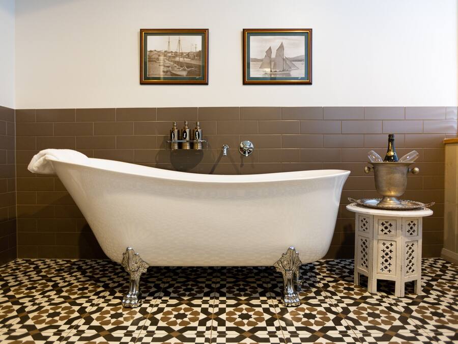Ein Badezimmer mit einer freistehenden Badewanne, zwei gerahmten Bildern an der Wand und einem Fliesenboden.