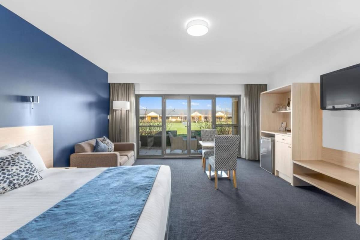 Hotellihuone, jossa on suuri sänky, työpöytä, tuoli, televisio ja parveke, jolta on näkymä.