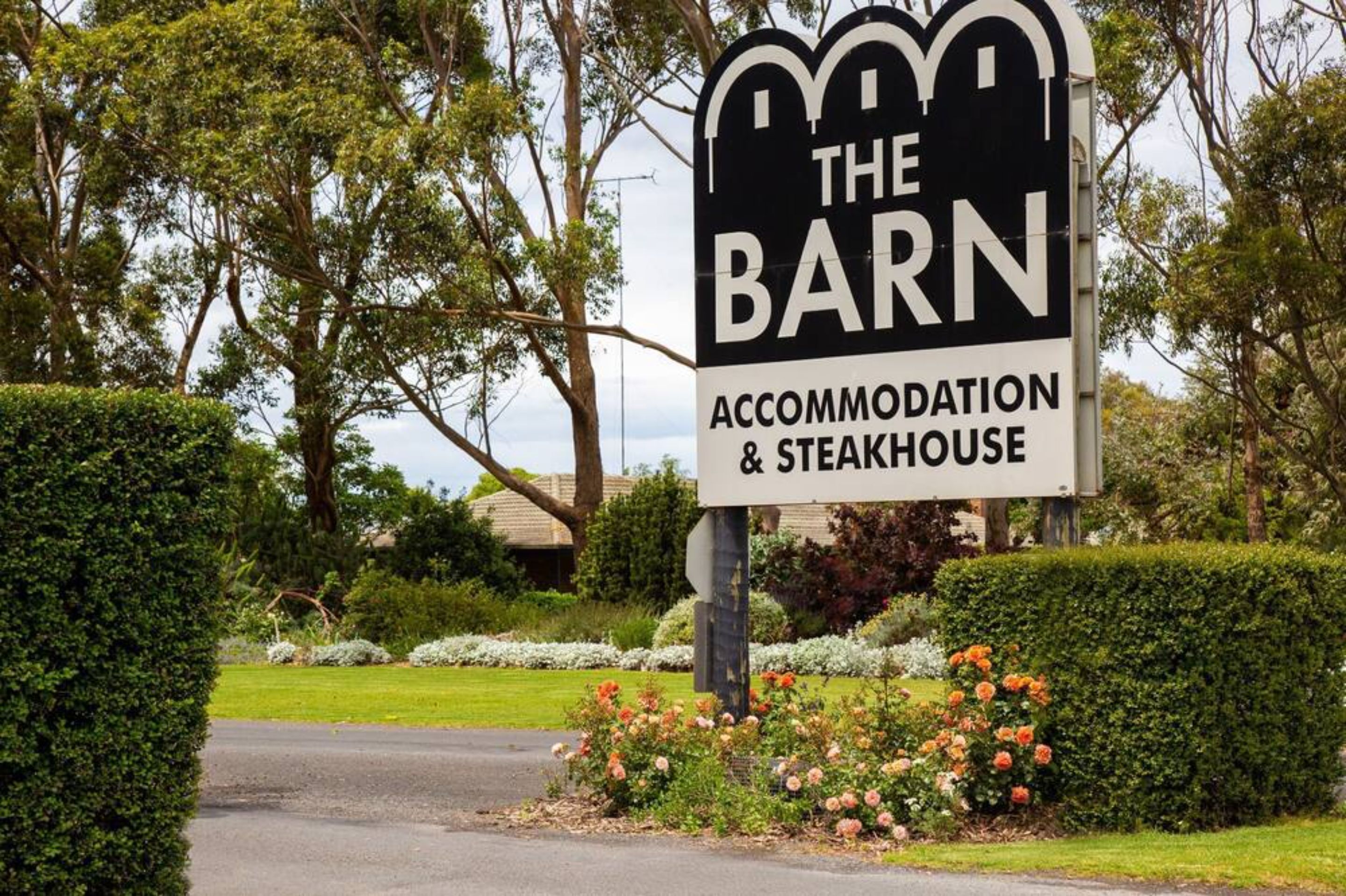 Señalización para el alojamiento y restaurante de carne ‘The Barn’, rodeado de jardines y árboles bien cuidados.