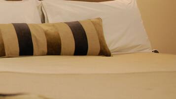 A bed with a striped pillow and a plain white pillow.