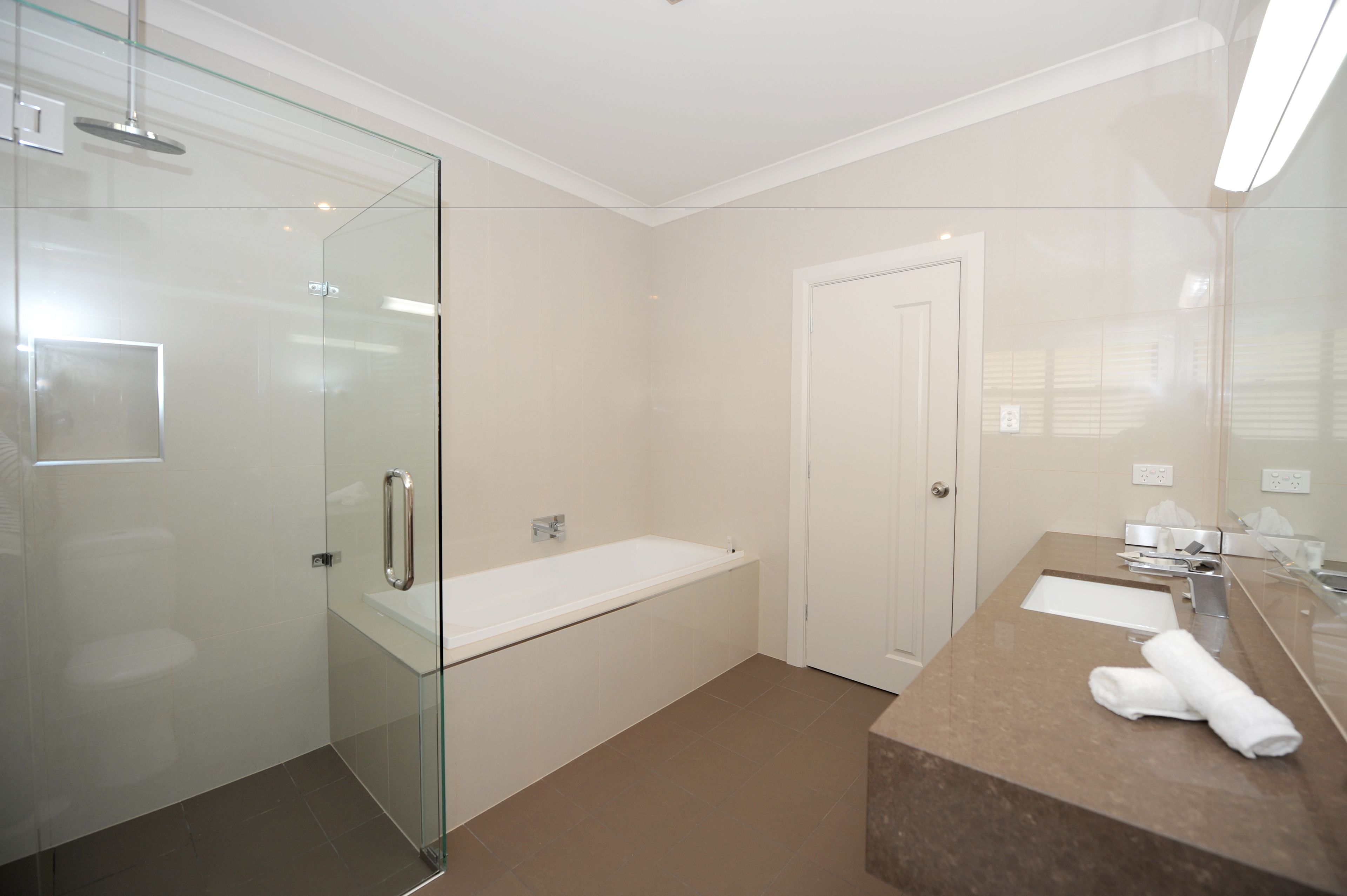 A modern bathroom with a glass shower enclosure, a standalone bathtub, and a marble vanity with a towel.