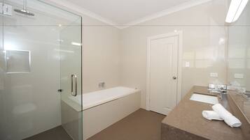 A modern bathroom with a glass shower enclosure, a standalone bathtub, and a marble vanity with a towel.