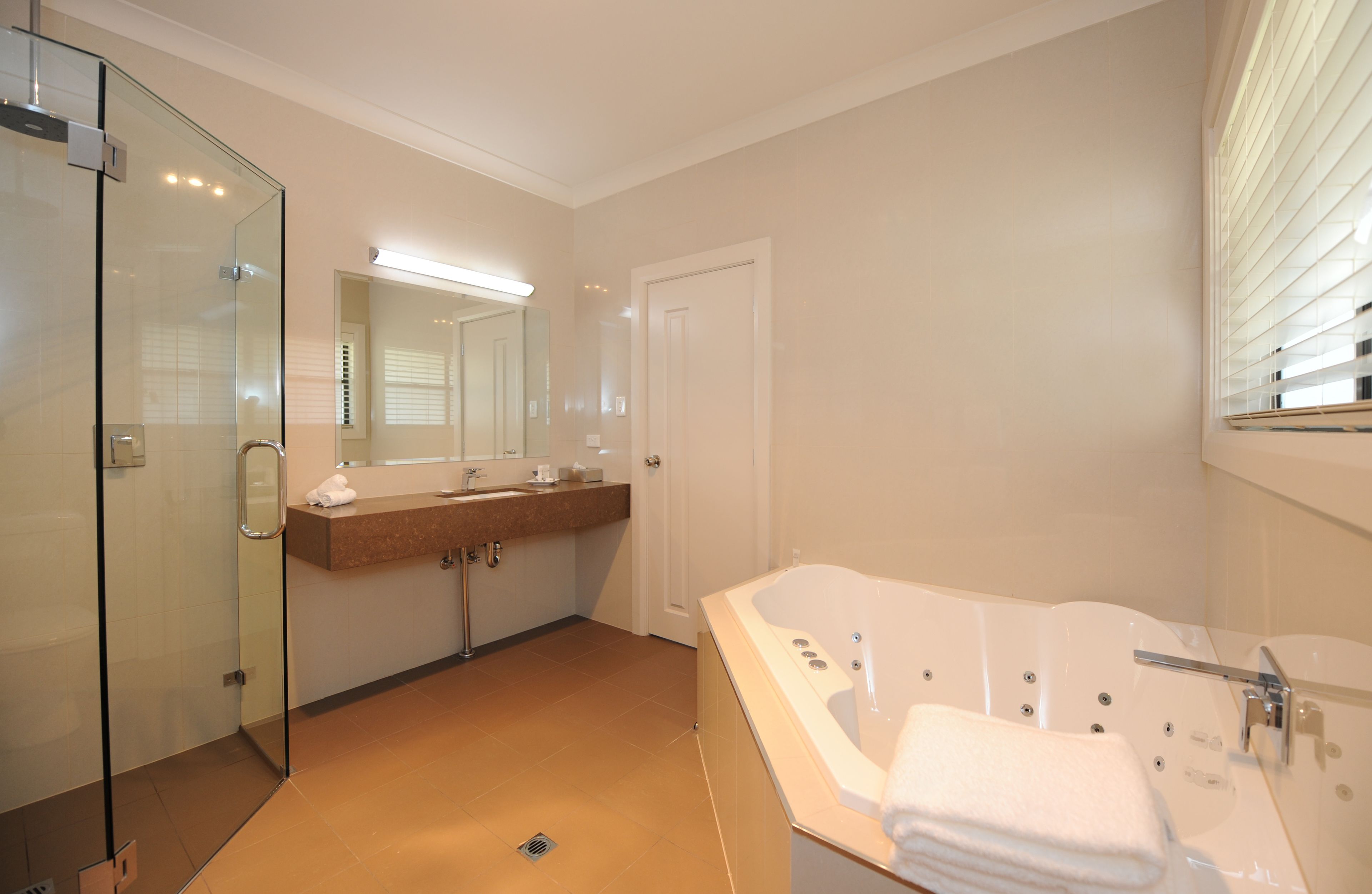 Une salle de bain moderne dotée d’une douche à parois de verre, d’une grande baignoire et d’un meuble-lavabo avec un miroir.