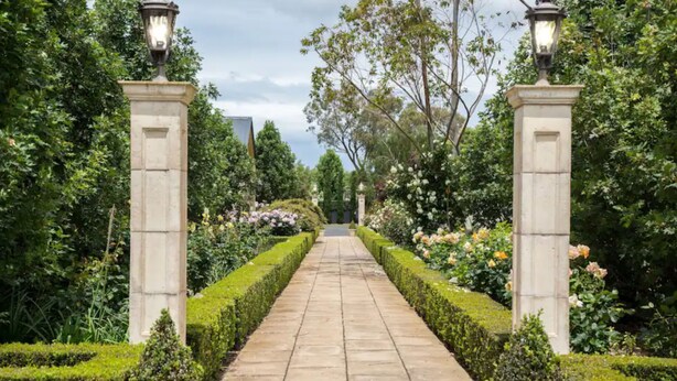 A garden pathway flanked by neatly trimmed hedges and flowering plants, leading to a building entrance. - The Barn Accommodation (Ob Flat)