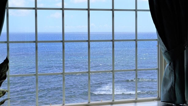 A window with a view of the ocean through a grid pattern. - Okinawa Ocean Front Hotel  (Chatan)