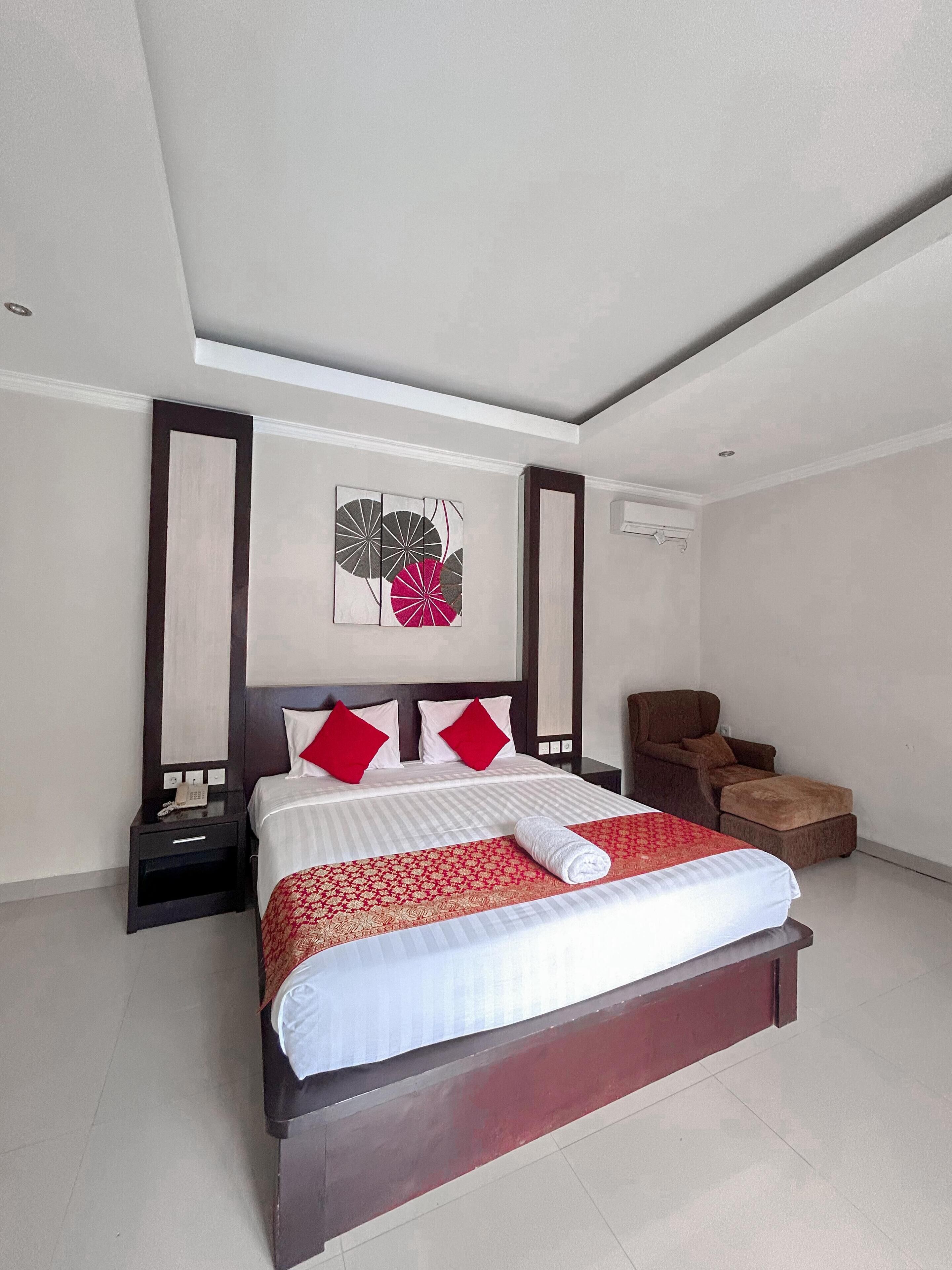 A modern hotel room with a large bed, a chair, and a small table.